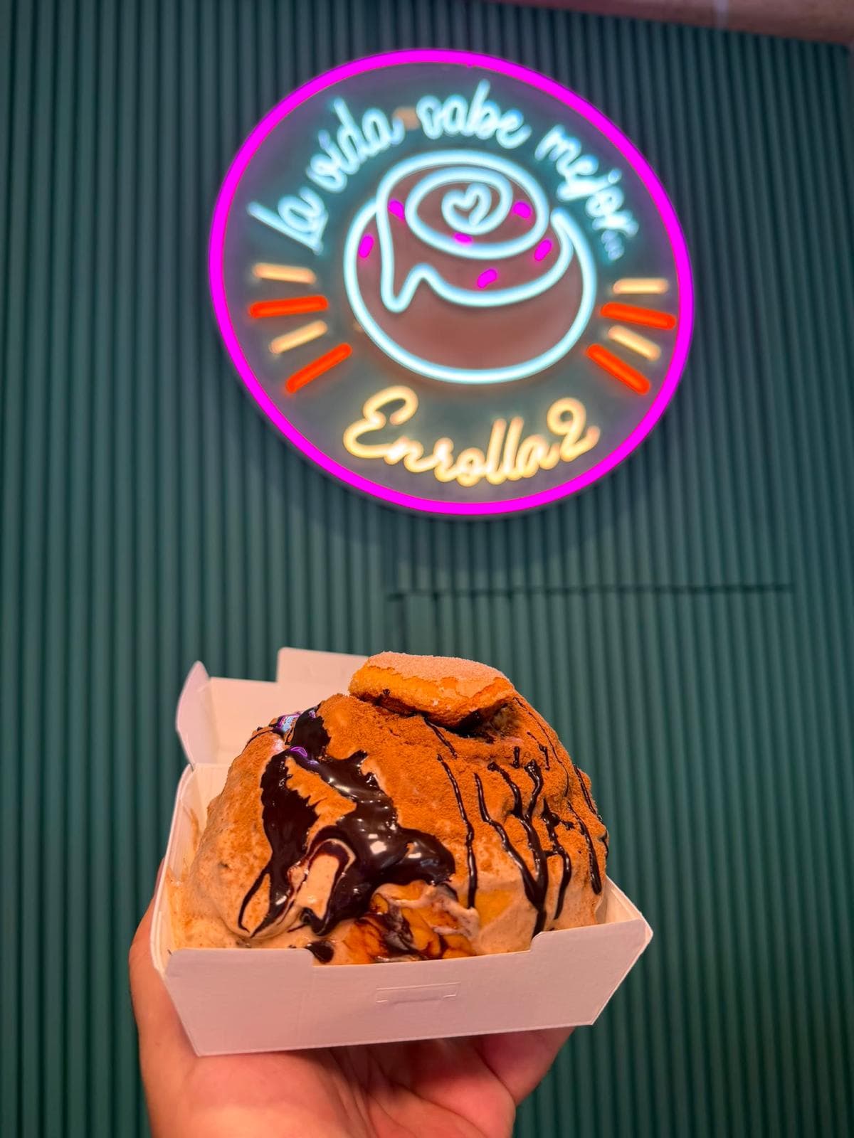 Roll de Enrolla2 frente al rótulo del local